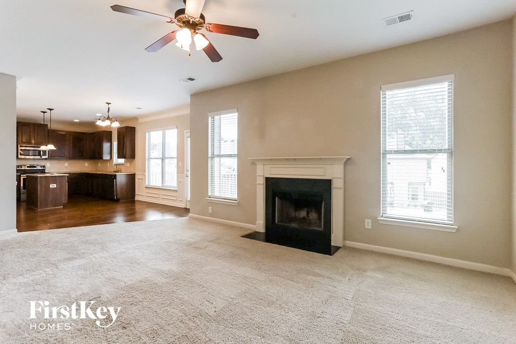 an empty living room with a fireplace and a kitchen