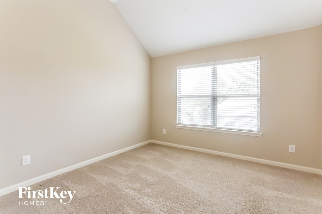 a bedroom with a window and a carpeted floor