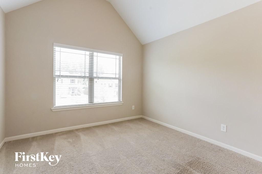 a spacious bedroom with carpet and a window