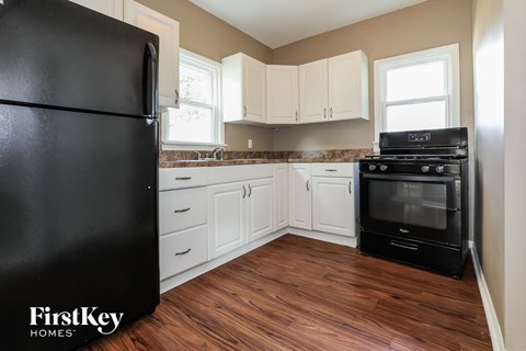 a kitchen with white cabinets and a black stove and refrigerator