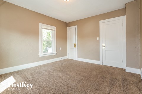 the living room of a house with carpet and two doors