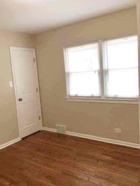 an empty room with a wooden floor and two windows