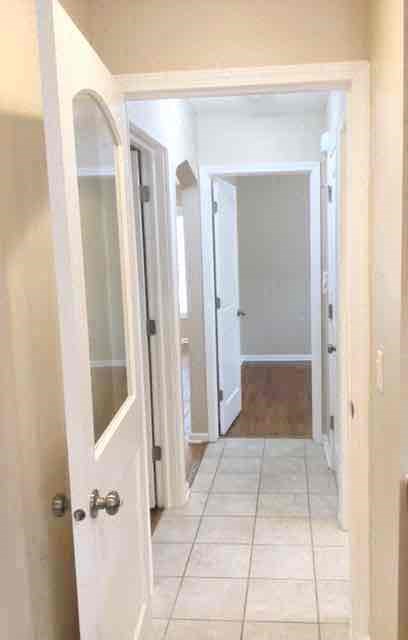 a hallway with a white tile floor and a white door