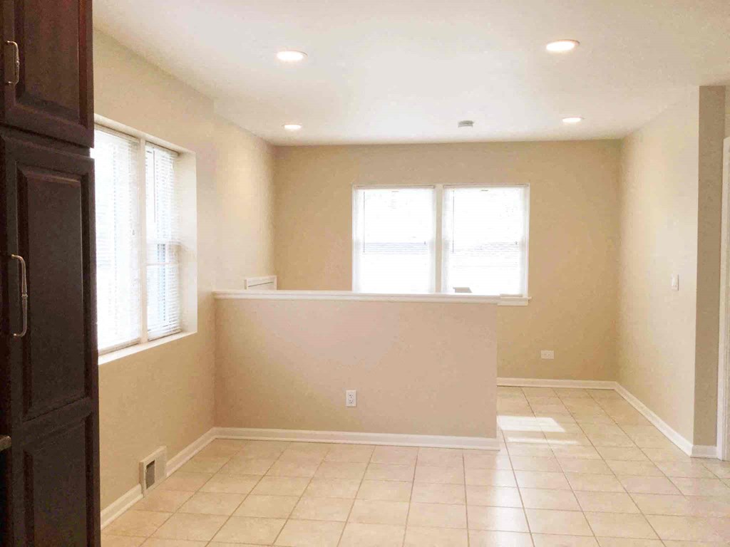 an empty living room with a large window and tiled floors