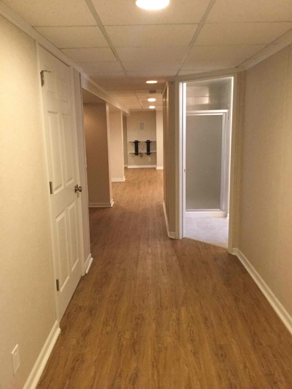 a hallway with wood floors and white walls and a white door