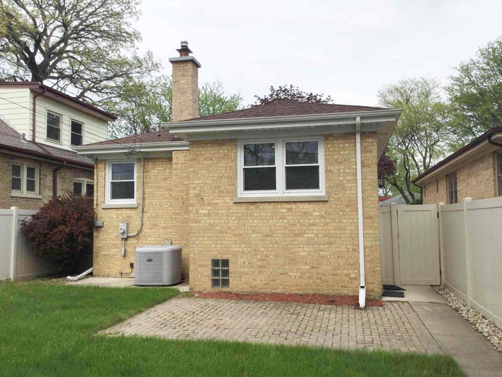 a small brick house with a yard and a white fence