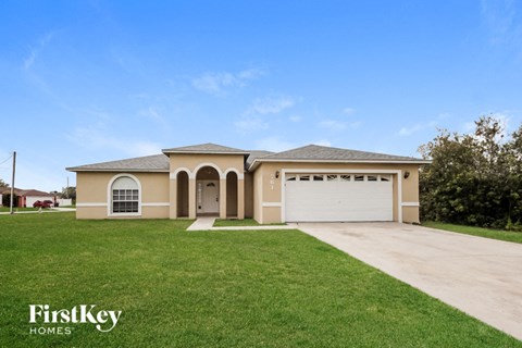a beige house with a garage and a lawn