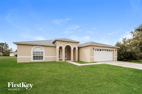 a beige house with a garage and a green lawn