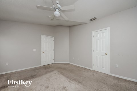 a bedroom with two doors and a ceiling fan