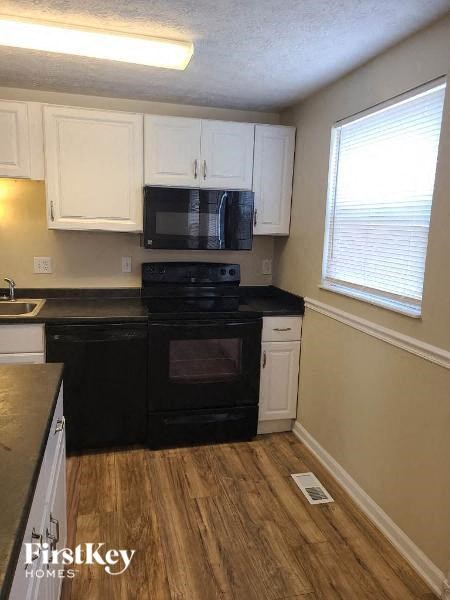 A kitchen with black appliances and white cabinets.