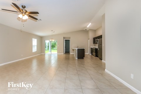 a spacious living room with tile flooring and a ceiling fan