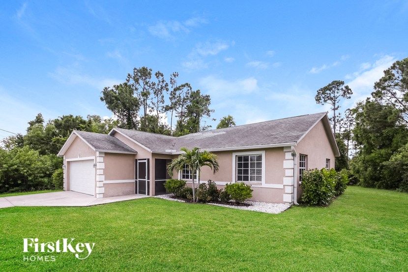 a small pink house with a green lawn and trees