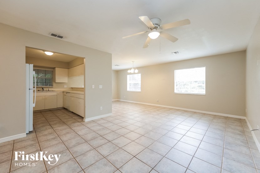 an empty living room and kitchen with a ceiling fan