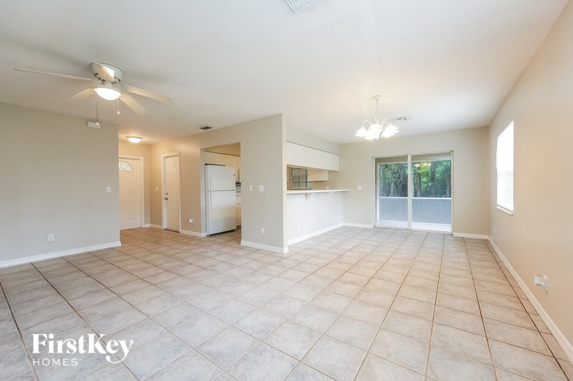 an empty living room with a kitchen and a ceiling fan