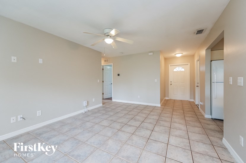 a spacious living room with tile flooring and a ceiling fan