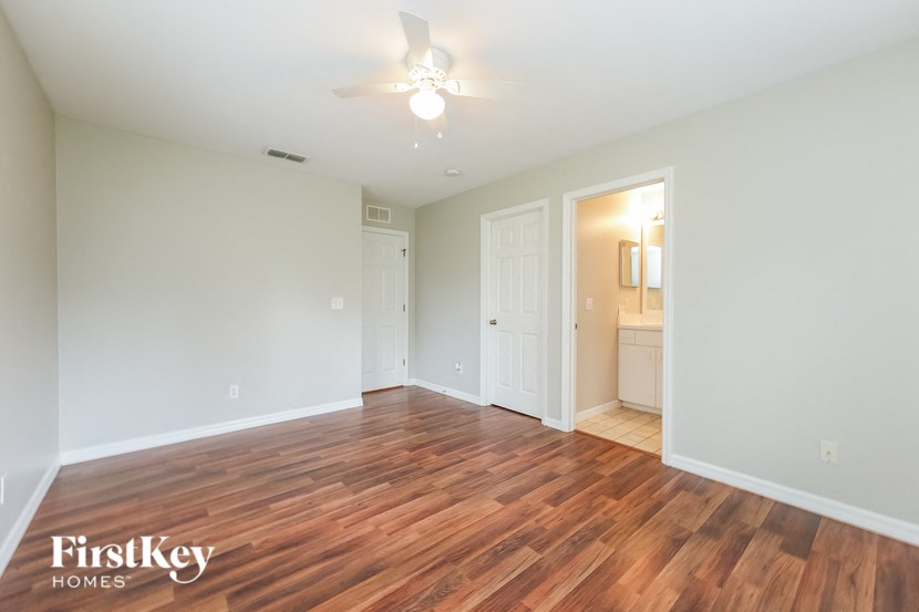 an empty living room with wood flooring and a ceiling fan