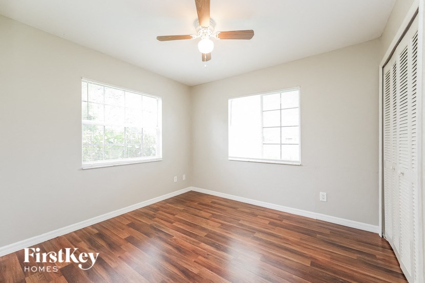 an empty living room with wood floors and a ceiling fan