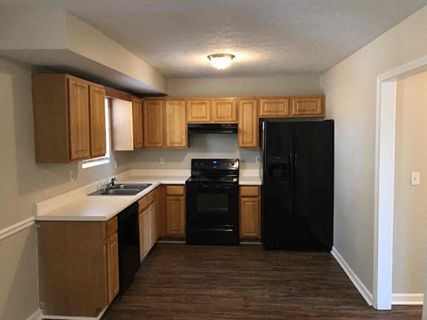 A kitchen with black appliances and wooden cabinets.