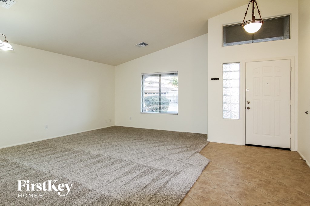 A spacious room with a rug on the floor and a door on the right side.