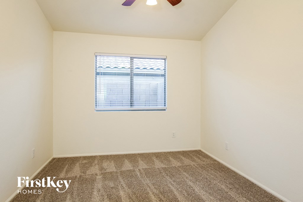 A room with a carpeted floor and a window with blinds.