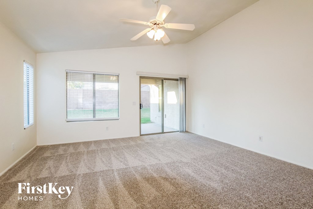 A spacious room with a carpeted floor and a ceiling fan.