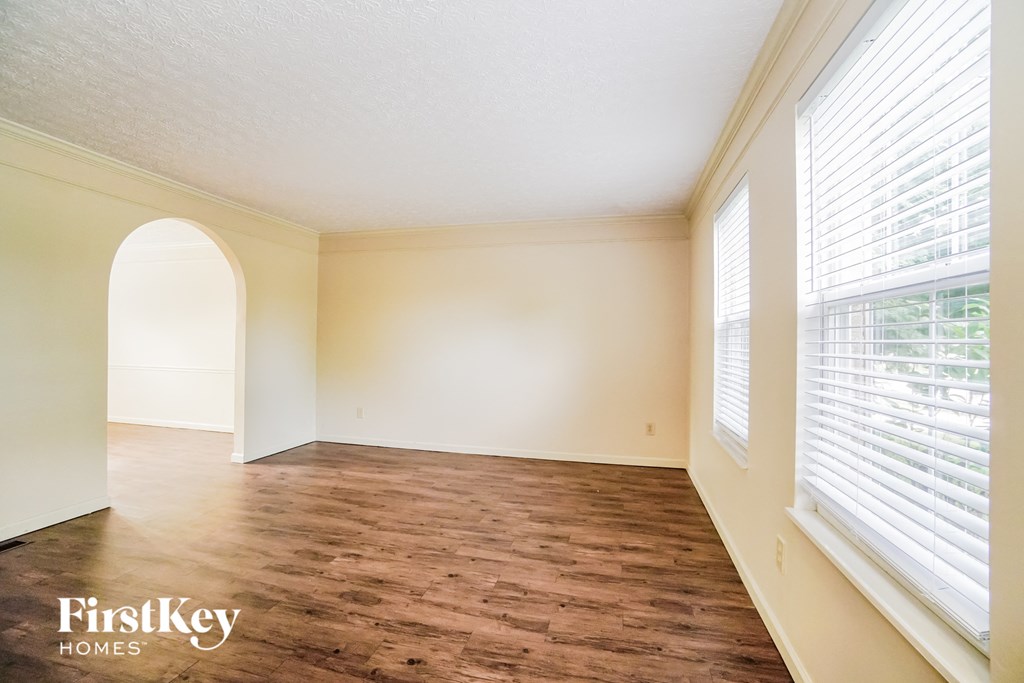 A room with wooden flooring and a window with blinds.