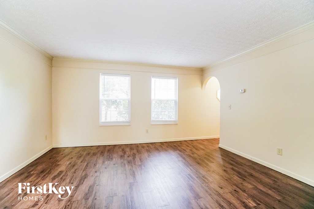A room with wooden floors and two windows.