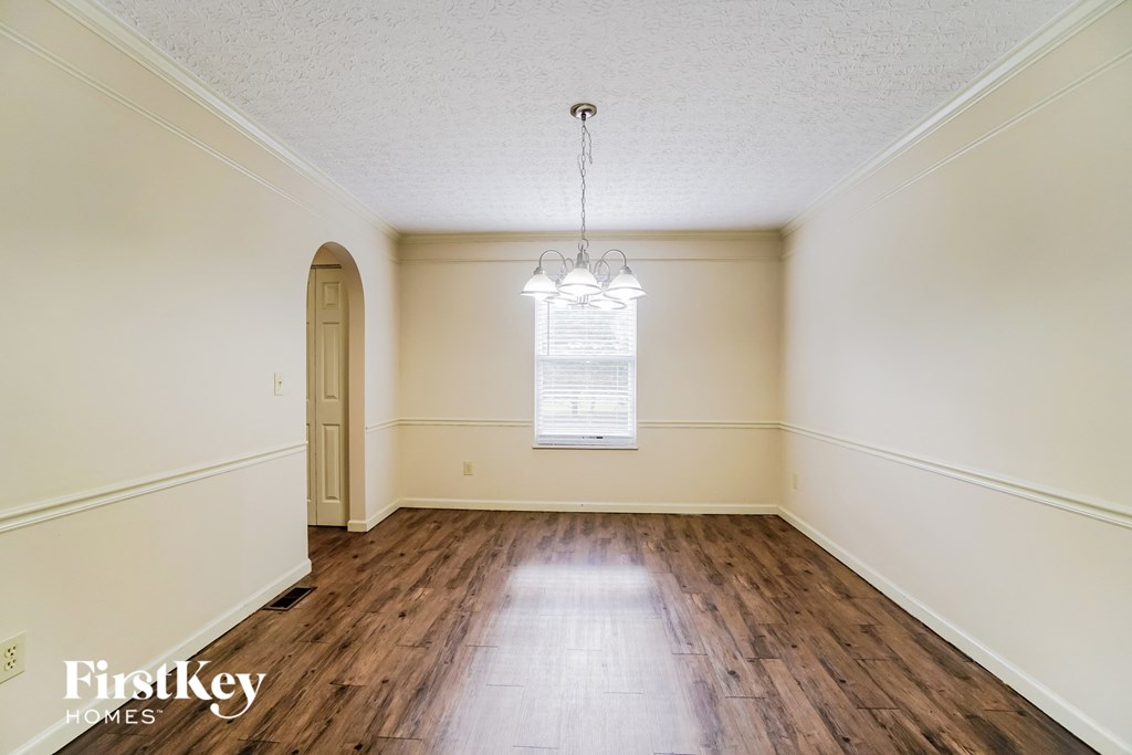 A room with wooden floors and a chandelier hanging from the ceiling.