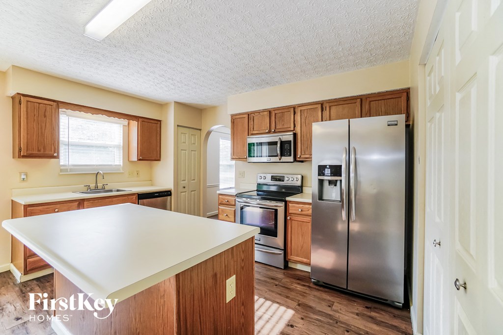 A kitchen with wooden cabinets and a stainless steel refrigerator.