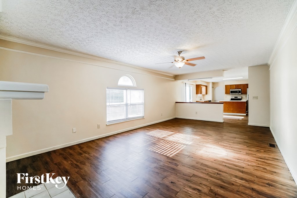 A spacious room with wooden floors and a ceiling fan.