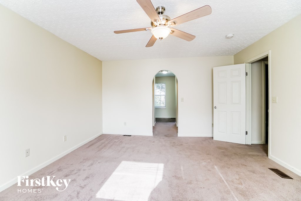 A room with a ceiling fan and a rug on the floor.