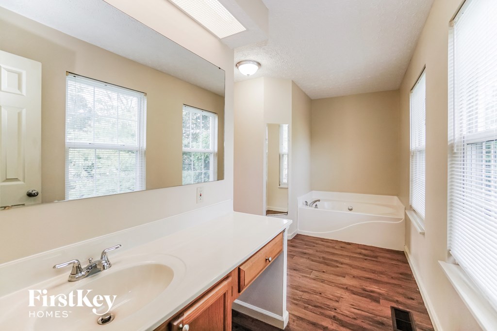 A bathroom with a white sink and wooden floors.