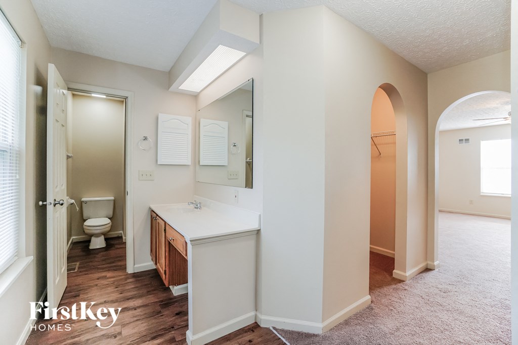 A bathroom with a toilet, sink, and mirror.