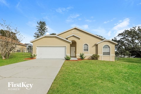 a beige house with a white garage door and a lawn