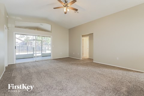 a spacious living room with carpet and a ceiling fan