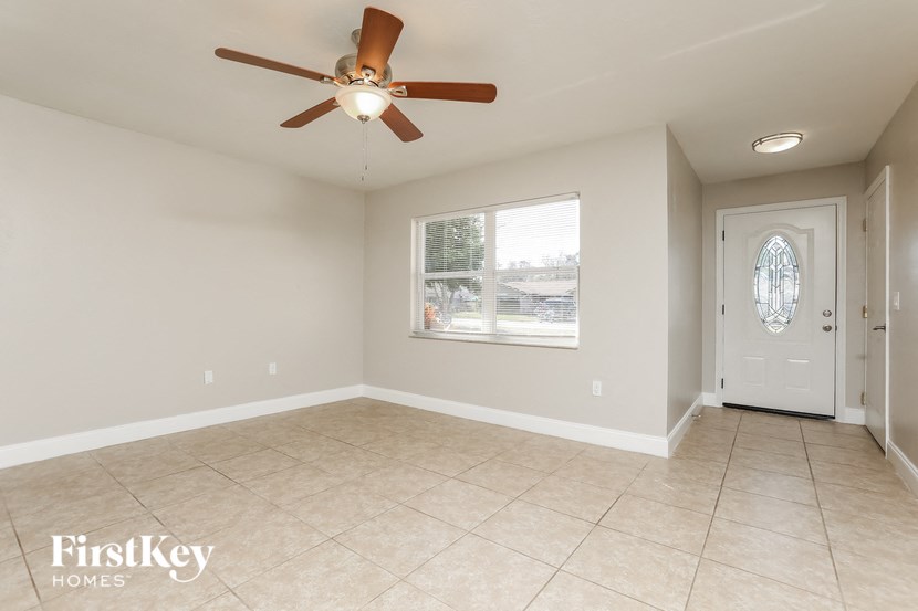 an empty living room with a ceiling fan and tiled floor