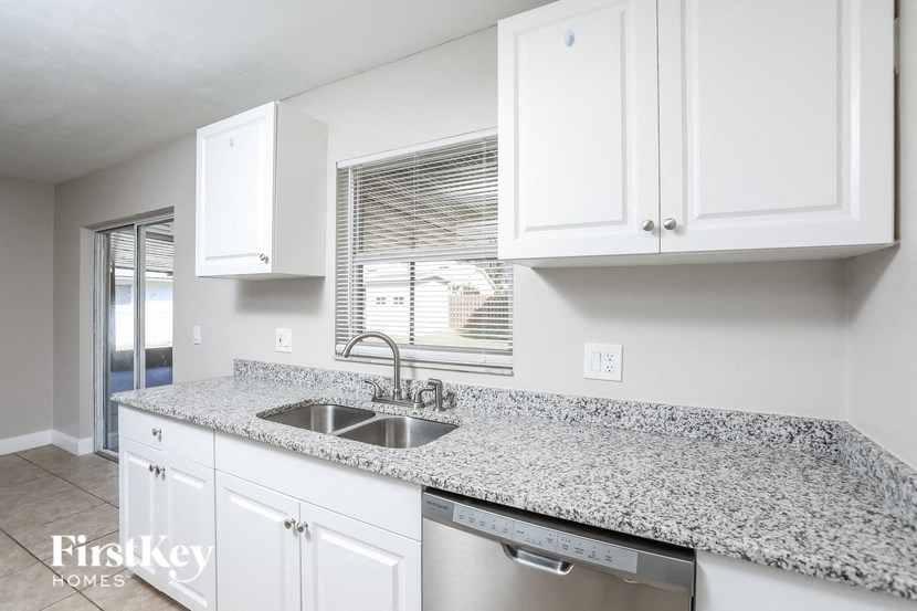a kitchen with white cabinets and granite counter tops and a sink