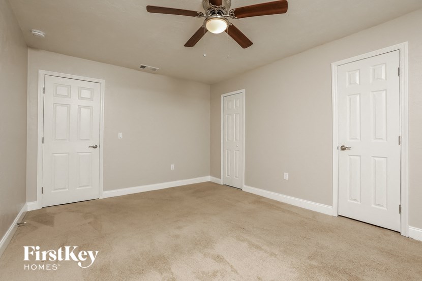 a empty living room with two doors and a ceiling fan