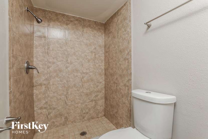 a tiled bathroom with a toilet and a shower