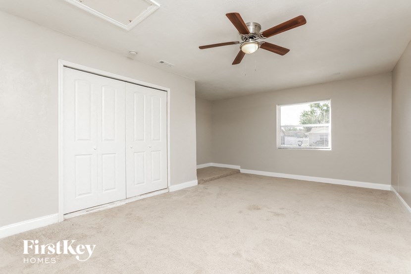 an empty bedroom with a ceiling fan and a closet
