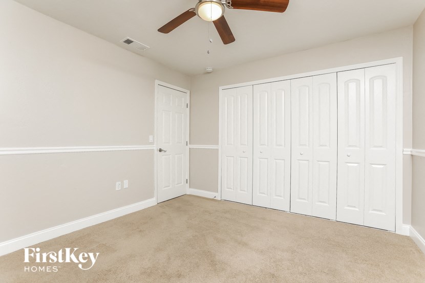 a bedroom with three closets and a ceiling fan