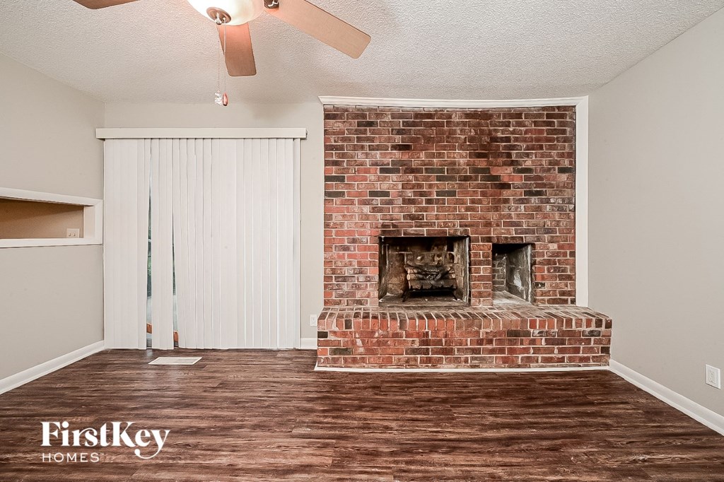 a living room with a brick fireplace and wooden floors