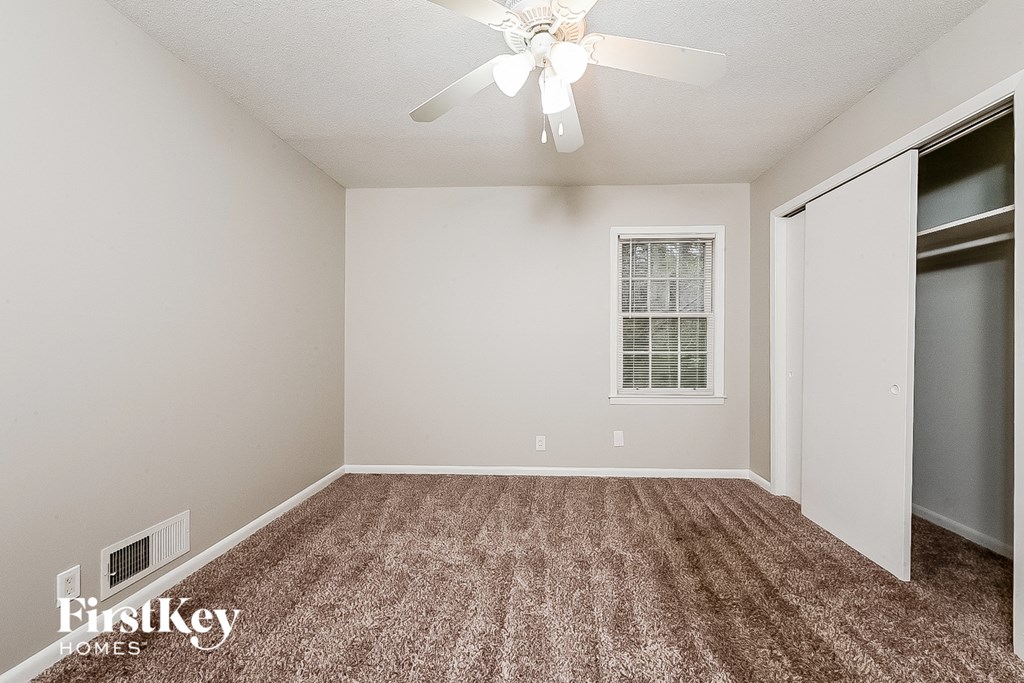the spacious living room with carpeting and a ceiling fan