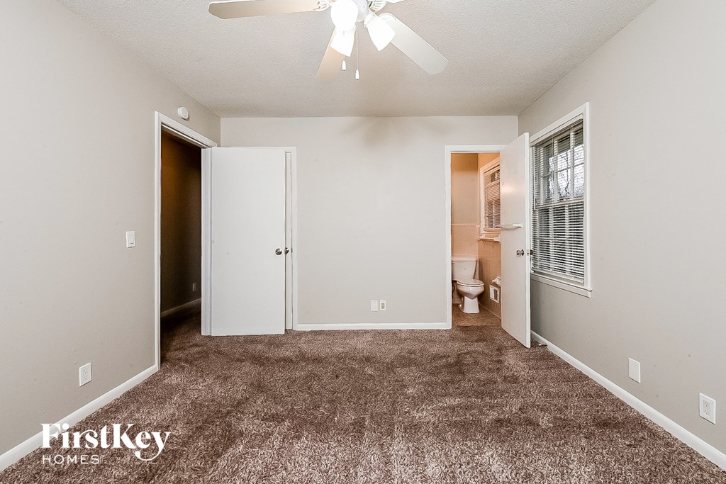 an empty living room with carpet and a ceiling fan