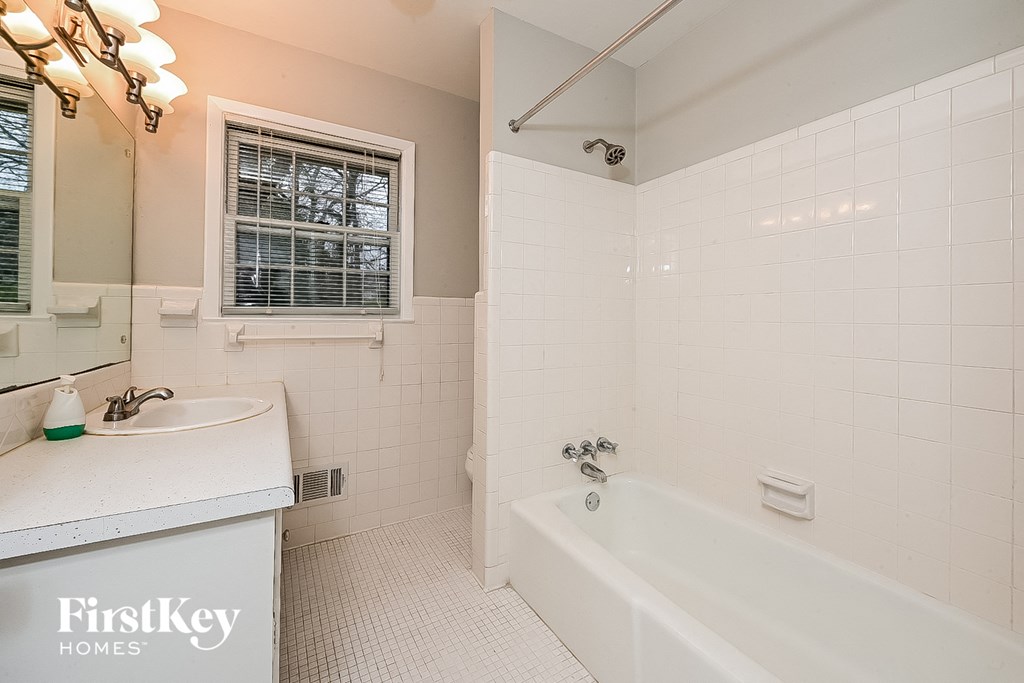 a white bathroom with a tub and a sink