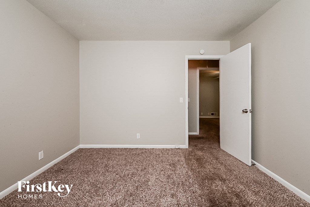 an empty room with carpet and a door to a hallway