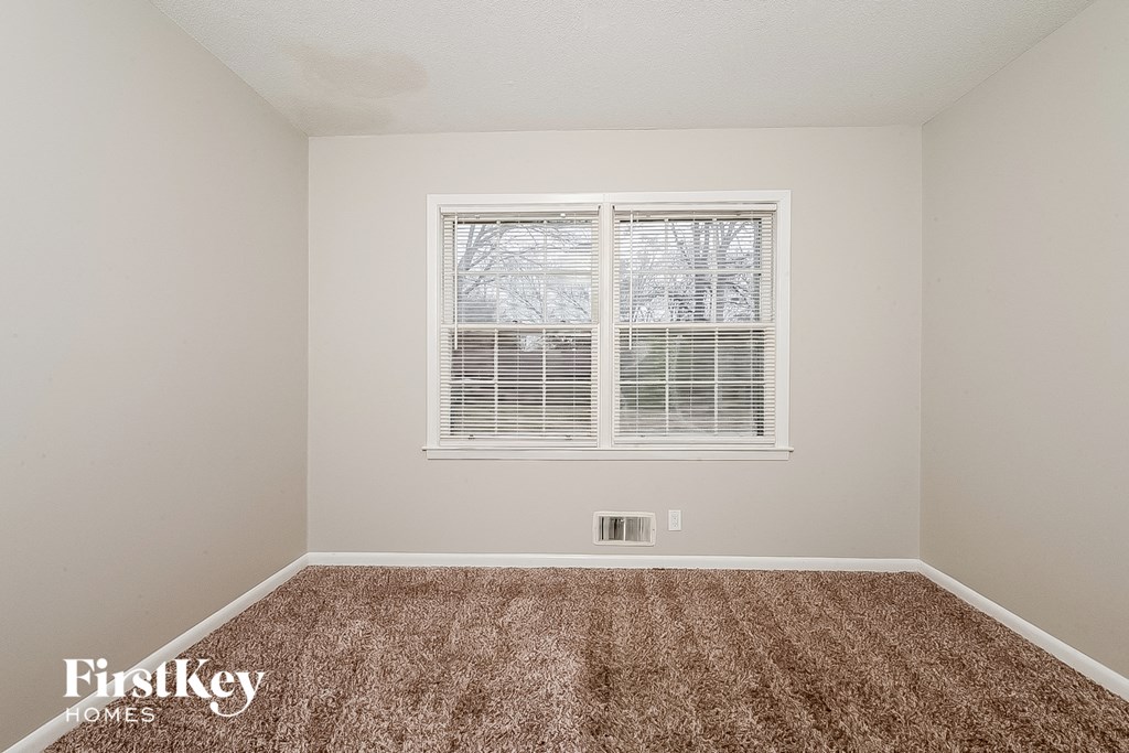 a spacious room with carpet and a window