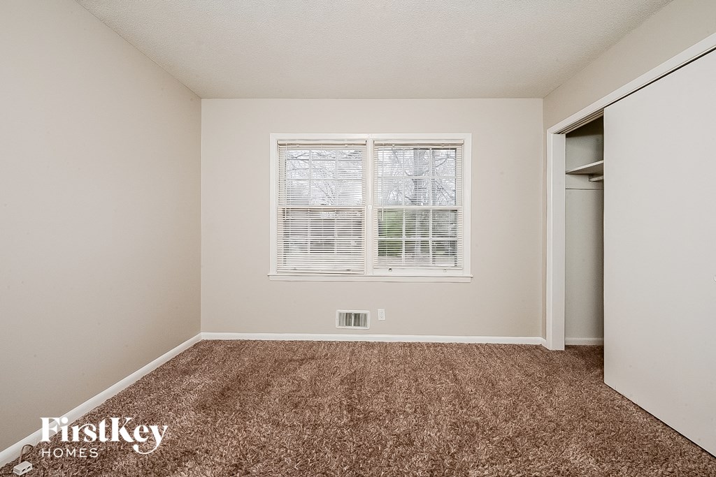 a bedroom with carpet and a window and a closet