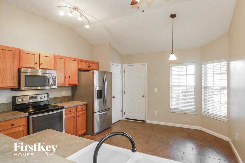 an empty kitchen with wooden cabinets and stainless steel appliances