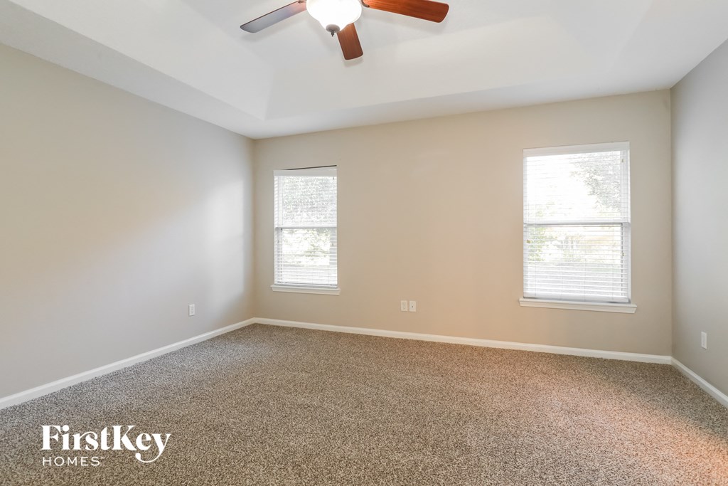 an empty room with a ceiling fan and two windows